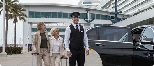 A chauffeur in uniform assists two women with luggage beside a black luxury car at the Port of Los Angeles San Pedro, with a modern cruise terminal and palm trees in the background.
