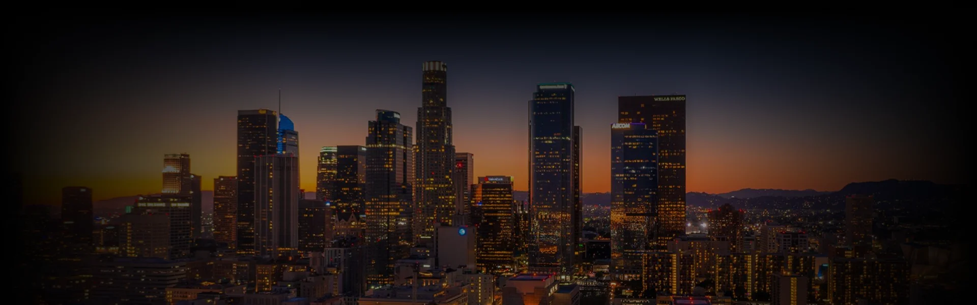 A vibrant city skyline of Los Angeles at sunset with illuminated skyscrapers, featuring Los Angeles Car Service.